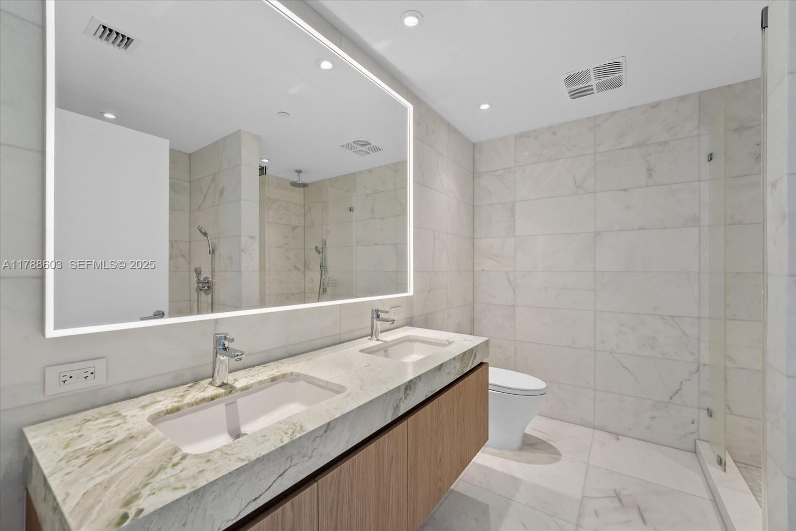 500 Alton Road, Unit 1105 Miami Beach, FL 33139 - Photo 20 of 69 a bathroom with a granite countertop bathtub sink vanity mirror and toilet