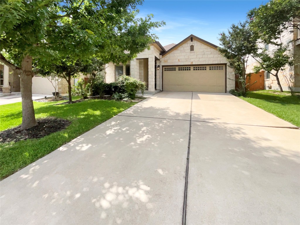 a view of a white house with a yard plants and large tree