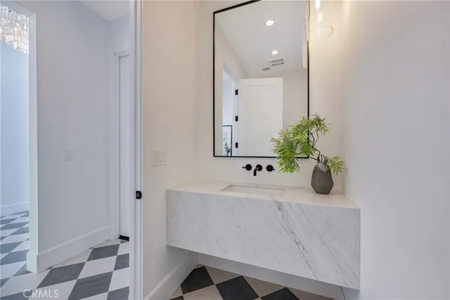 a bathroom with a sink and mirror with bathtub
