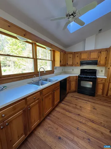 a kitchen with stainless steel appliances granite countertop a sink a stove cabinets and wooden floor