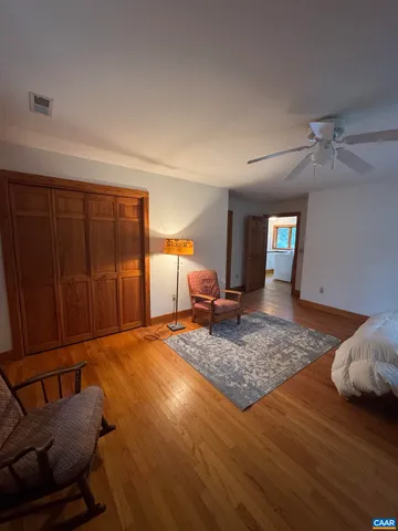 a spacious bedroom with a bed a dresser and wooden floor