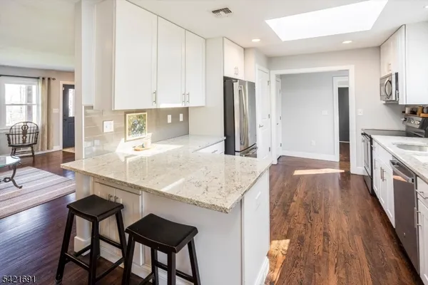 a kitchen with stainless steel appliances granite countertop a stove refrigerator and a refrigerator with wooden floor