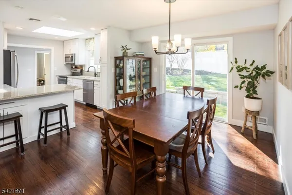 a view of a dining room and livingroom with furniture wooden floor a chandelier