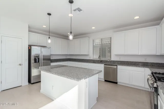 a kitchen with stainless steel appliances granite countertop a sink a stove and a refrigerator