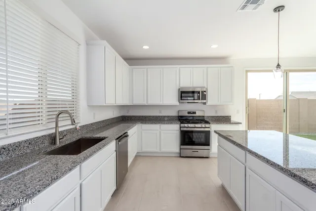 a kitchen with stainless steel appliances granite countertop a sink a stove and cabinets