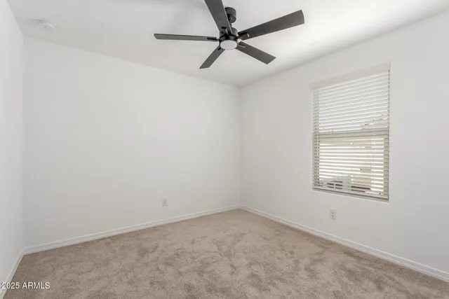 an empty room with a window and a fan