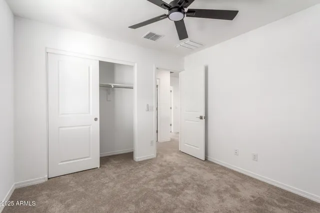 an empty room with closet and a chandelier fan