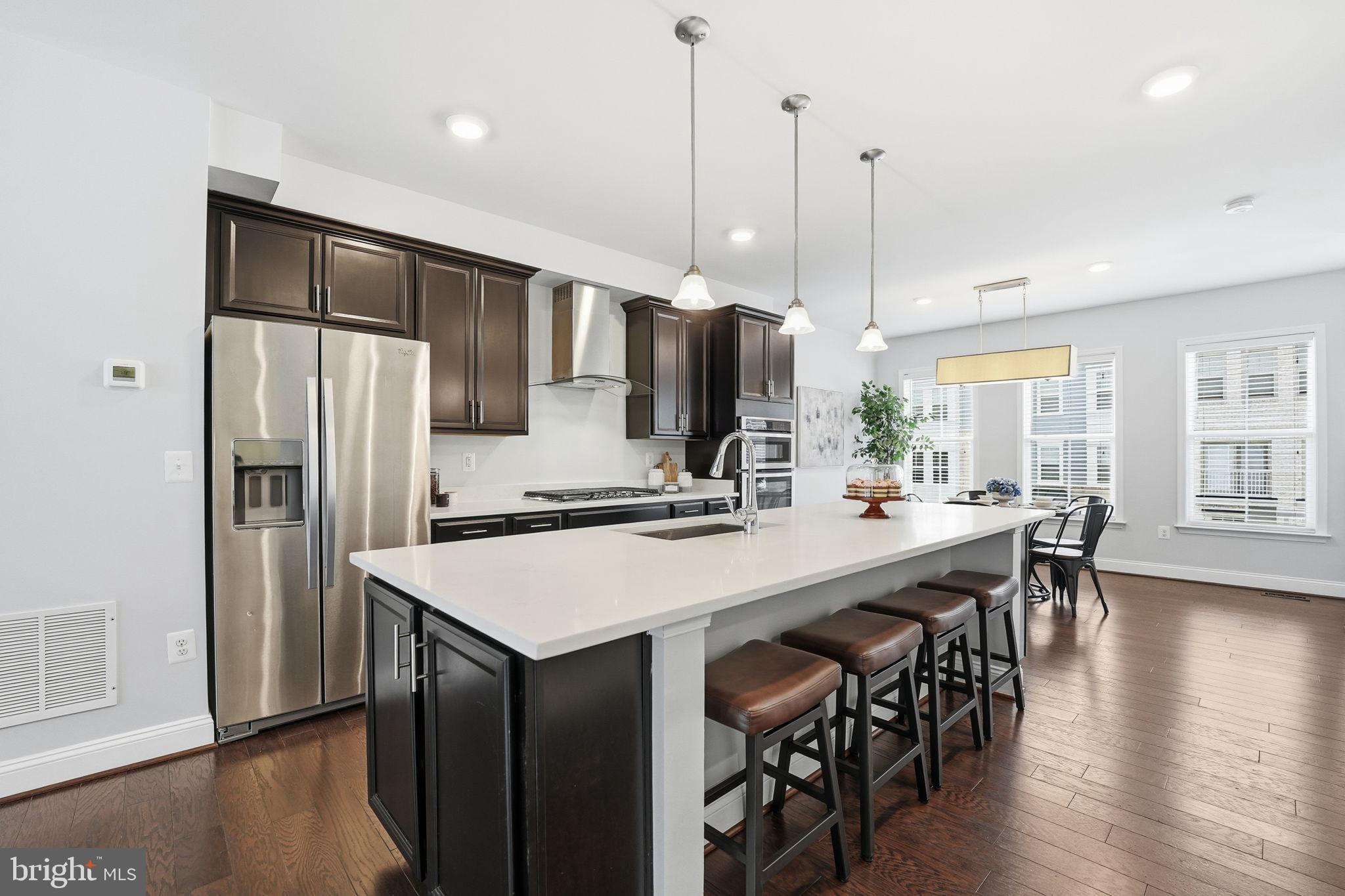 17354 Redshank Road Dumfries, VA 22026 - Photo 10 of 65 a kitchen with stainless steel appliances granite countertop a refrigerator a sink a stove a dining table and chairs with wooden floor