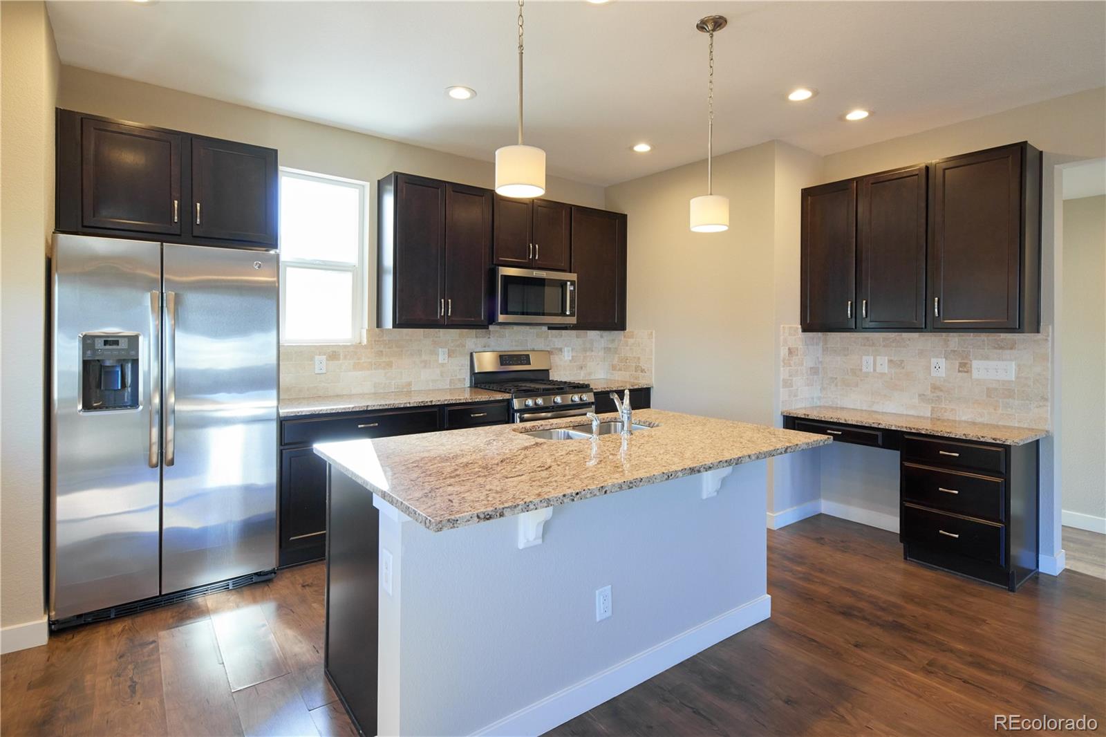 11225 Colony Row Broomfield, CO 80021 - Photo 7 of 31 a kitchen with stainless steel appliances granite countertop a sink a stove and a refrigerator