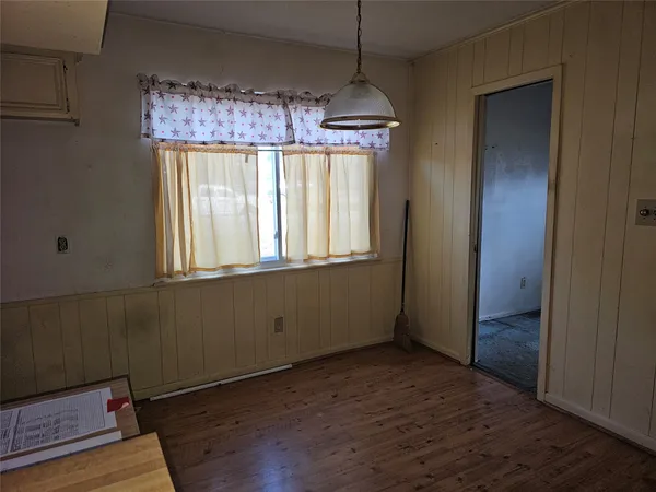 an empty room with wooden floor chandelier and windows