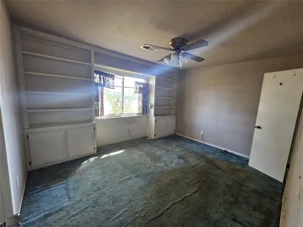 a view of empty room with window and ceiling fan