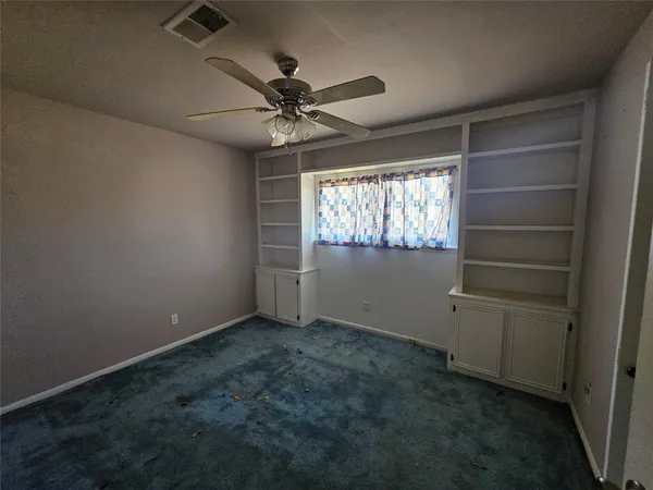 an empty room with windows and fan