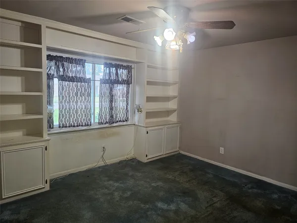 en empty room with windows and ceiling fan