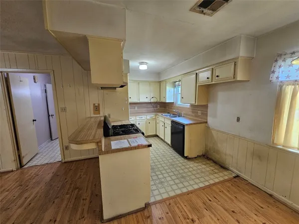 a view of an empty room with wooden floor and fan