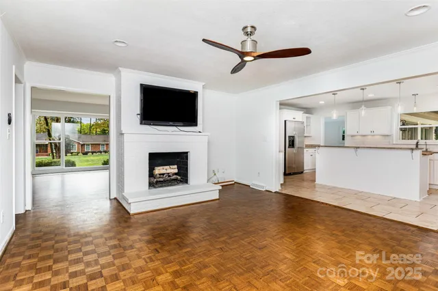 a view of a livingroom with a fireplace a ceiling fan and windows