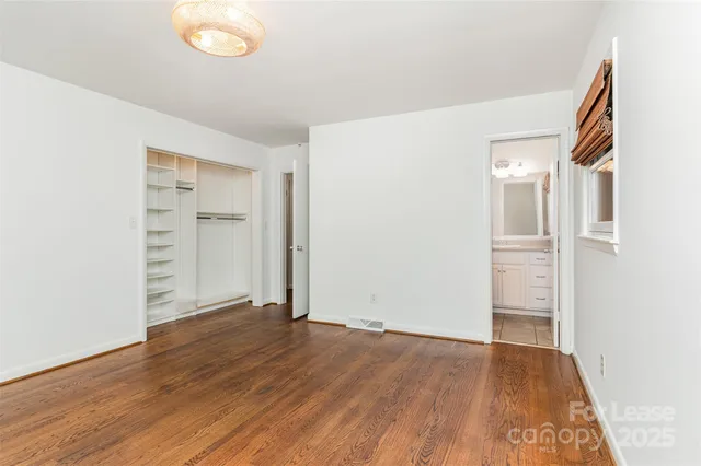 an empty room with wooden floor & closet and windows