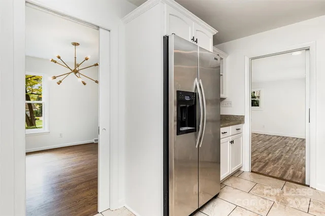a view of a refrigerator in kitchen and an empty room
