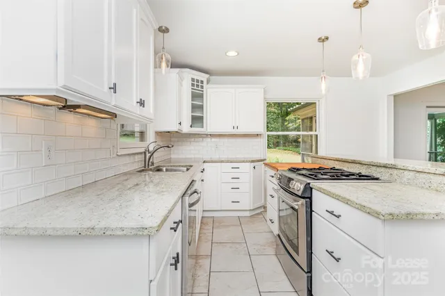 a kitchen with a stove a sink and white cabinets