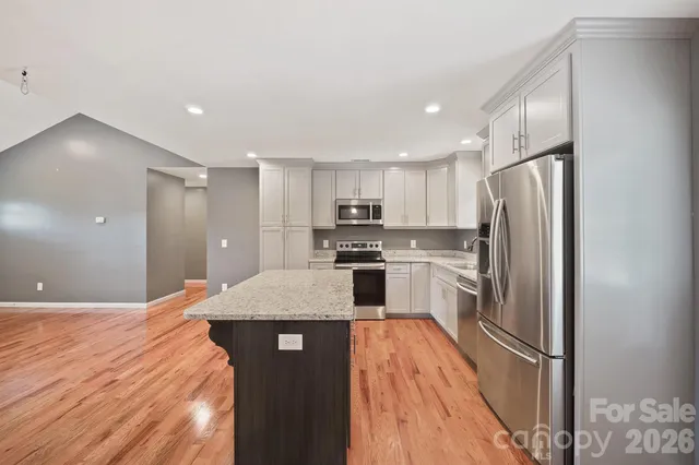 a kitchen with stainless steel appliances granite countertop a refrigerator a sink a stove and oven