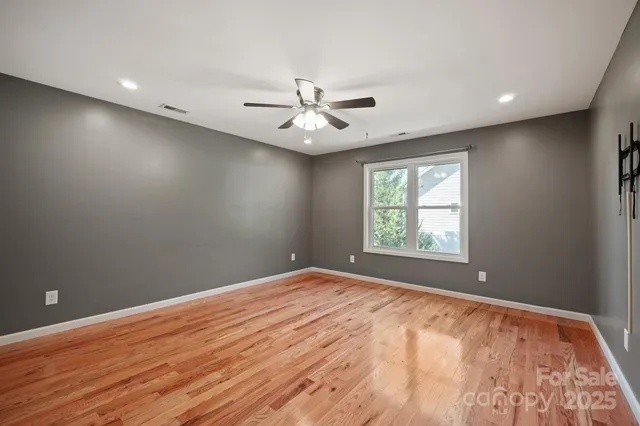 an empty room with windows and ceiling fan