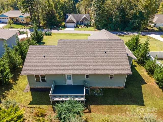 an aerial view of a house with swimming pool large trees and buildings