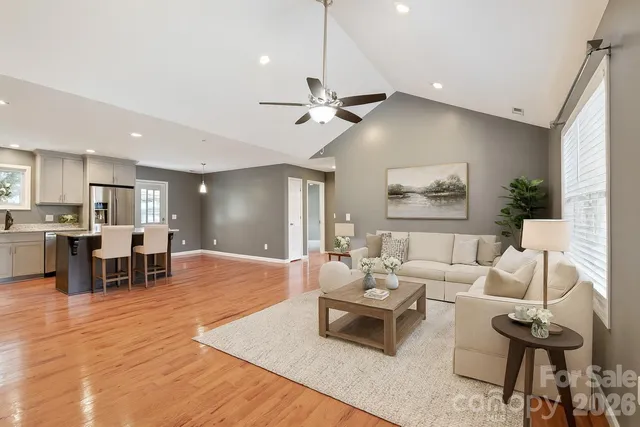 a living room with furniture kitchen view and a wooden floor