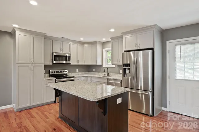a kitchen with a refrigerator a sink and wooden floor