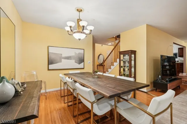 a dining room with wooden floor a chandelier a wooden table and chairs