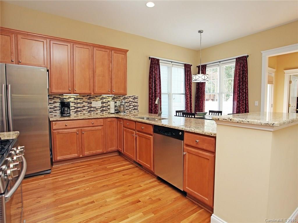 1865 2nd Baxter Crossing Fort Mill, SC 29708 - Photo 11 of 24 a kitchen with stainless steel appliances granite countertop a refrigerator a sink dishwasher and wooden cabinets with wooden floor