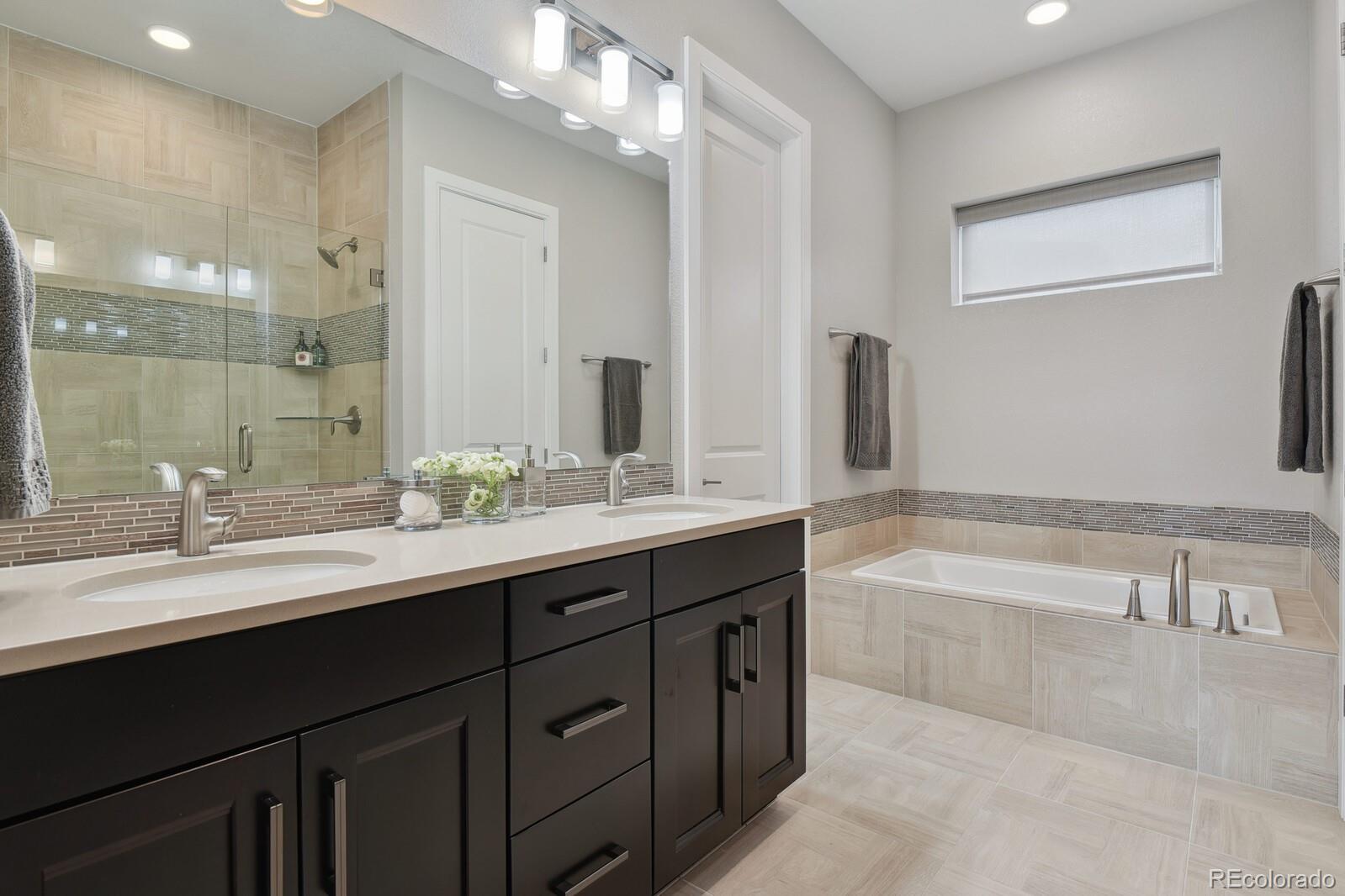 76 Niagara Street Denver, CO 80230 - Photo 15 of 44 a bathroom with a bathtub double vanity sink and a large mirror