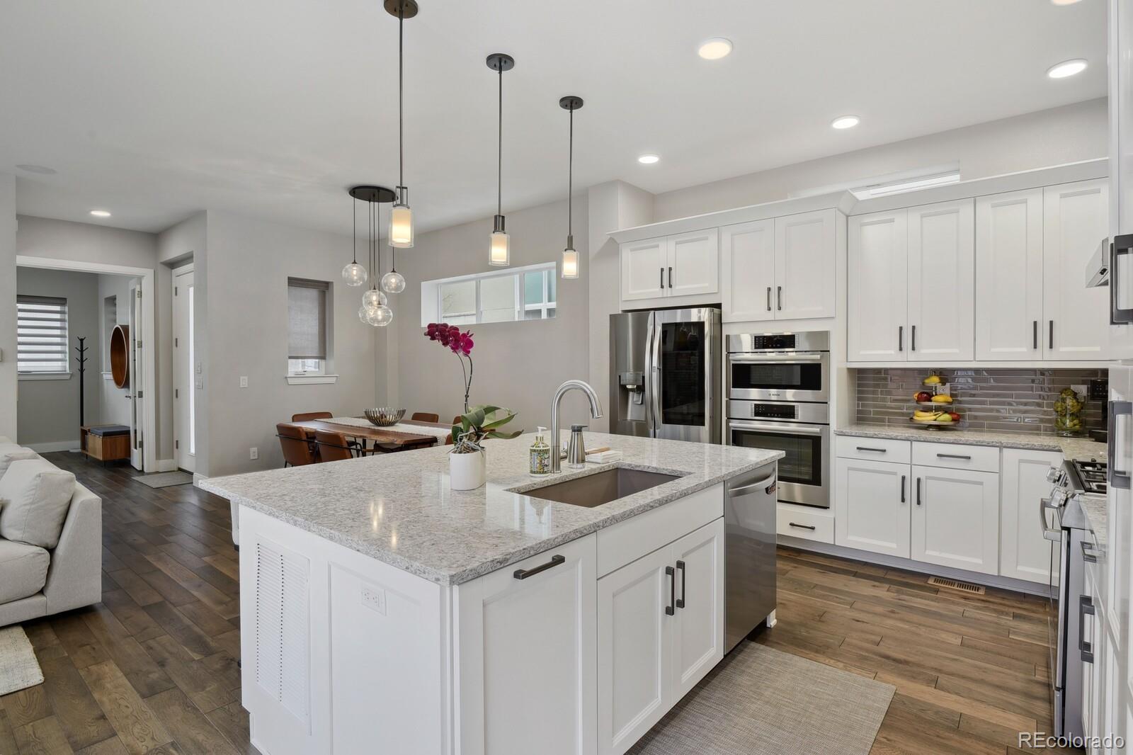 76 Niagara Street Denver, CO 80230 - Photo 7 of 44 a kitchen with stainless steel appliances kitchen island granite countertop a sink and dishwasher a refrigerator with white cabinets