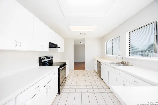 a large white kitchen with a stove a sink a microwave and a refrigerator