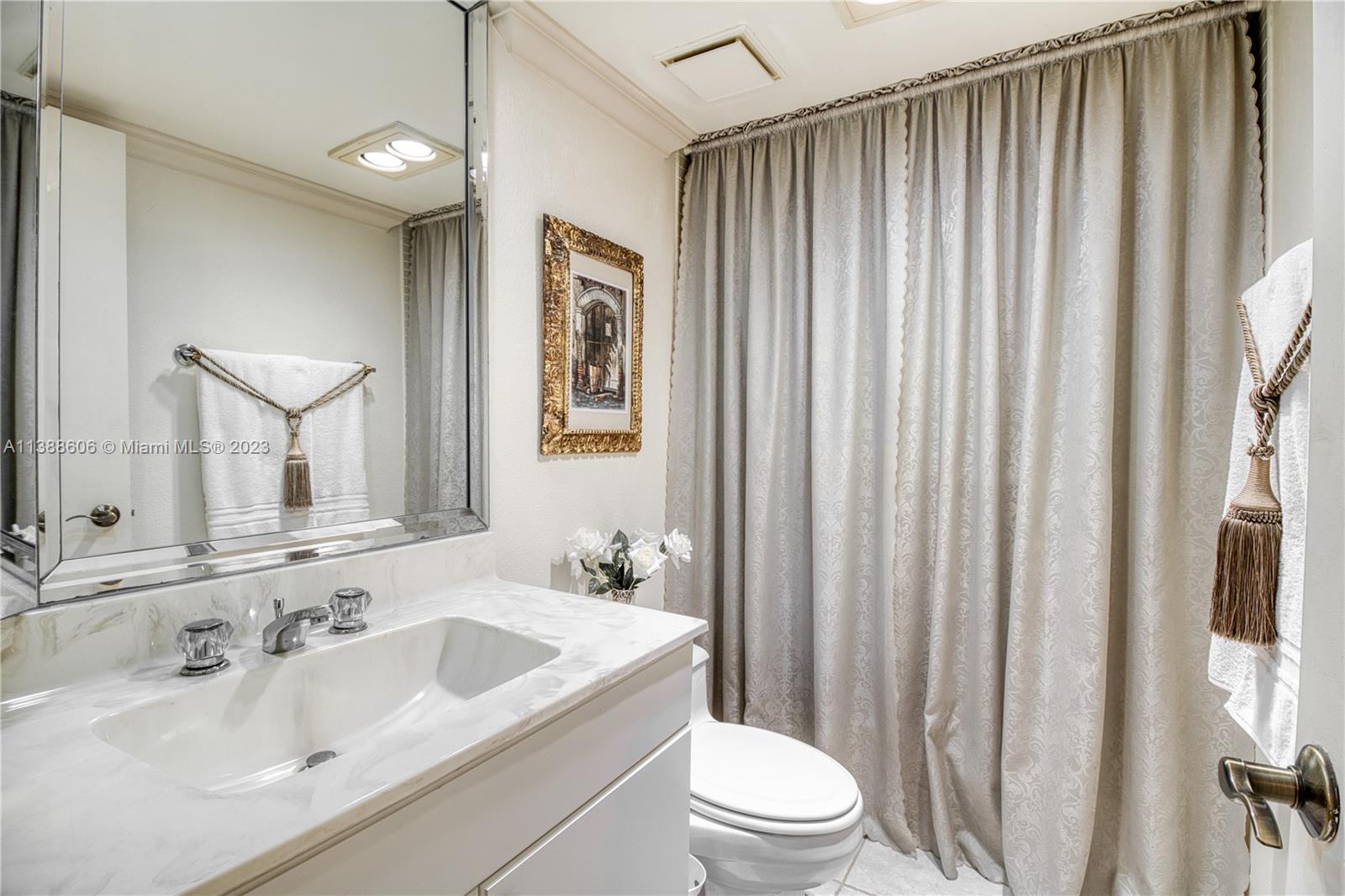 520 Brickell Key Drive, Unit A810 Miami, FL 33131 - Photo 19 of 20 a bathroom with a sink a toilet a mirror and shower curtain