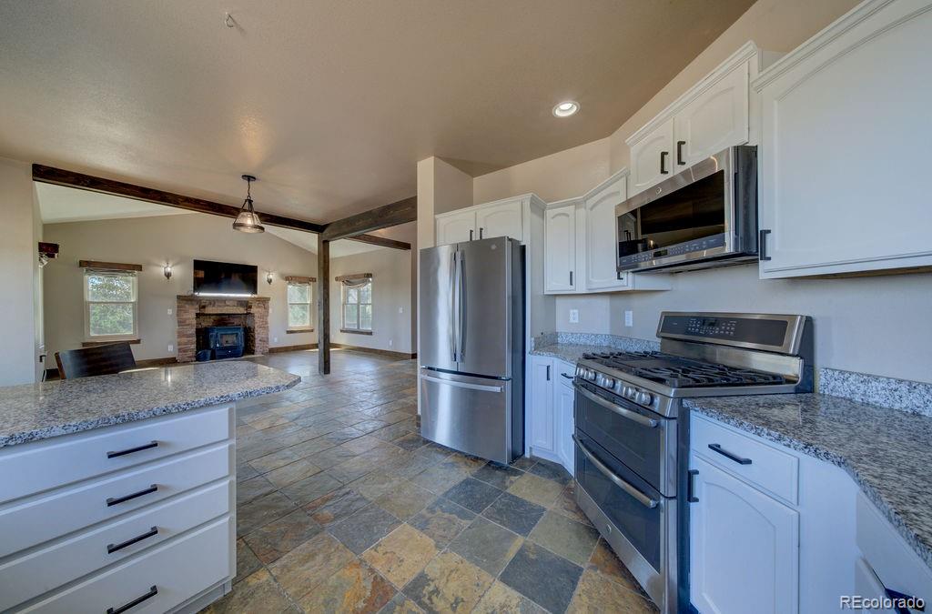 14965 Tanner Trail Elbert, CO 80106 - Photo 11 of 40 a kitchen with stainless steel appliances granite countertop a stove top oven a refrigerator and a sink