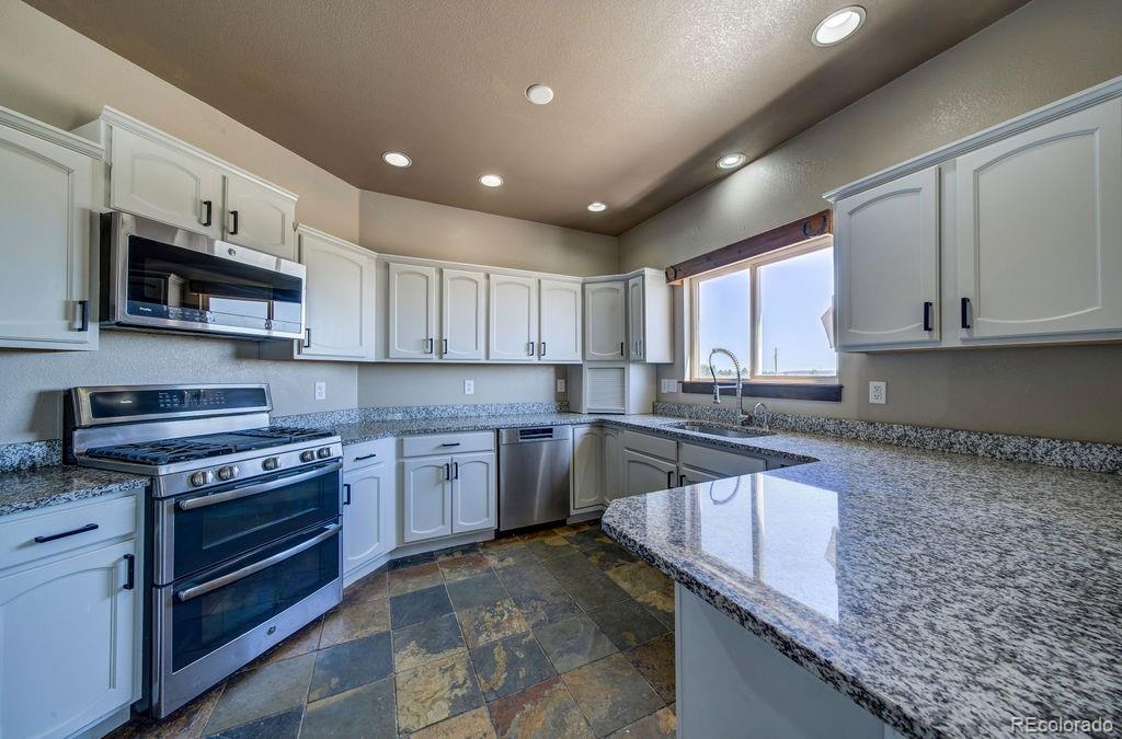 14965 Tanner Trail Elbert, CO 80106 - Photo 8 of 40 a kitchen with stainless steel appliances granite countertop a sink stove and microwave