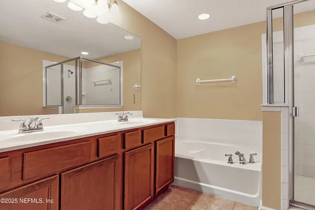 a bathroom with a bathtub shower sink vanity and mirror
