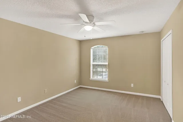 an empty room with windows and ceiling fan