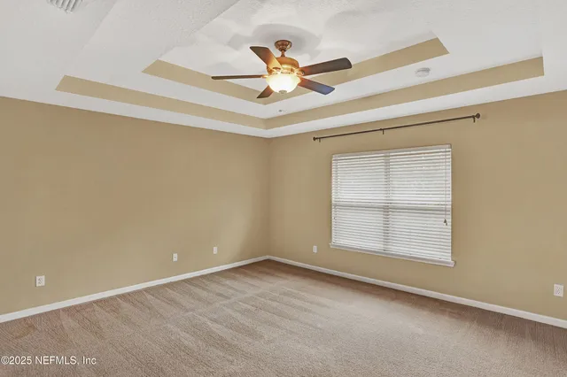 an empty room with ceiling fan and window
