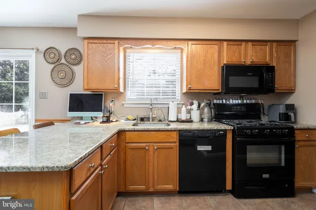 a kitchen with granite countertop a stove top oven a sink and a microwave