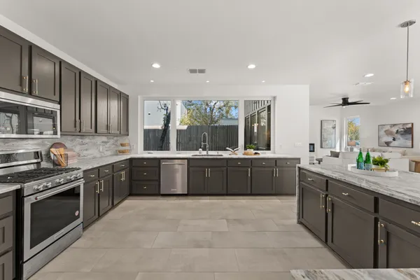 a large kitchen with stainless steel appliances granite countertop a stove a sink dishwasher a refrigerator and wooden cabinets