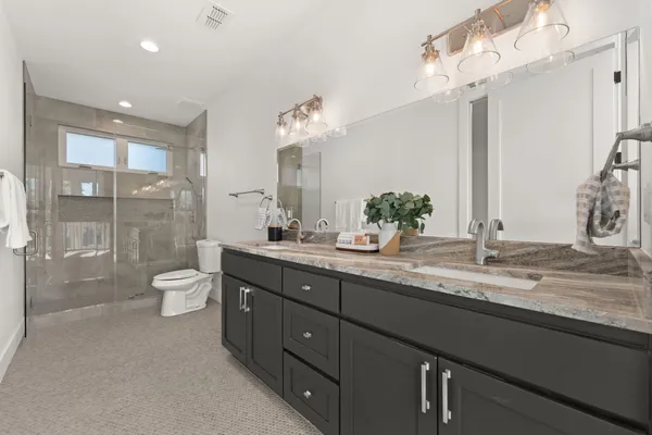 a bathroom with a granite countertop sink a toilet and a shower
