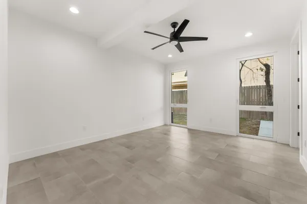 an empty room with windows and fan