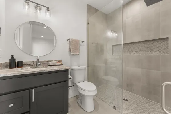 a bathroom with a toilet a sink a mirror and shower