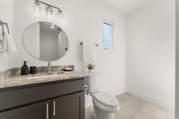 a bathroom with a granite countertop toilet sink and mirror