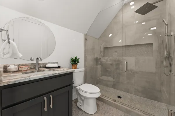 a bathroom with a granite countertop sink a toilet and shower
