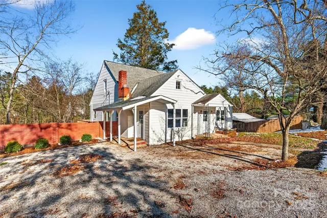 a view of a white house with a large tree next to a yard