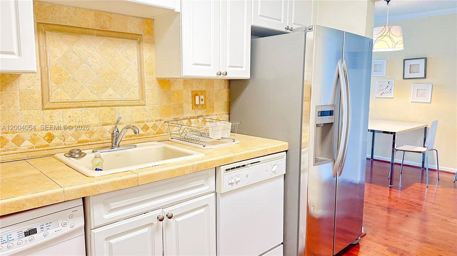 2501 South Ocean Drive, Unit 820 Hollywood, FL 33019 - Photo 11 of 12 a kitchen with a sink a refrigerator a stove and a dining table with wooden floor
