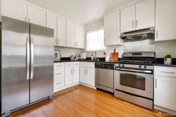 a kitchen with appliances cabinets and a wooden floor