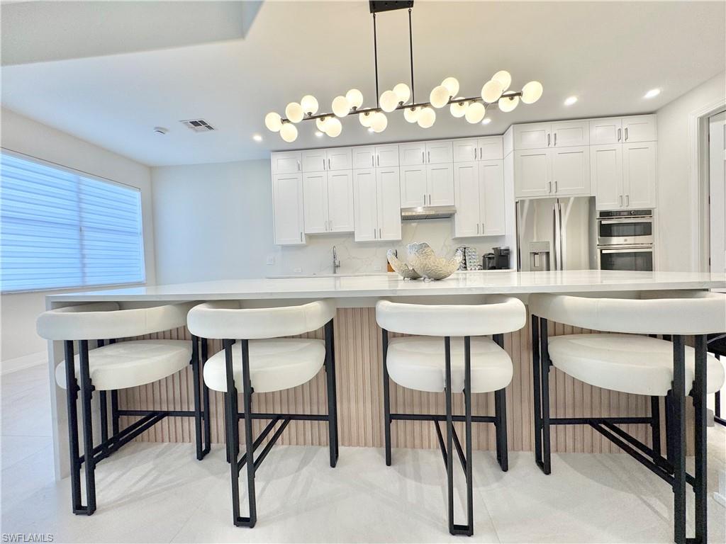 12667 Biscayne Court Naples, FL 34105 - Photo 19 of 39 a kitchen with kitchen island a dining table and chairs