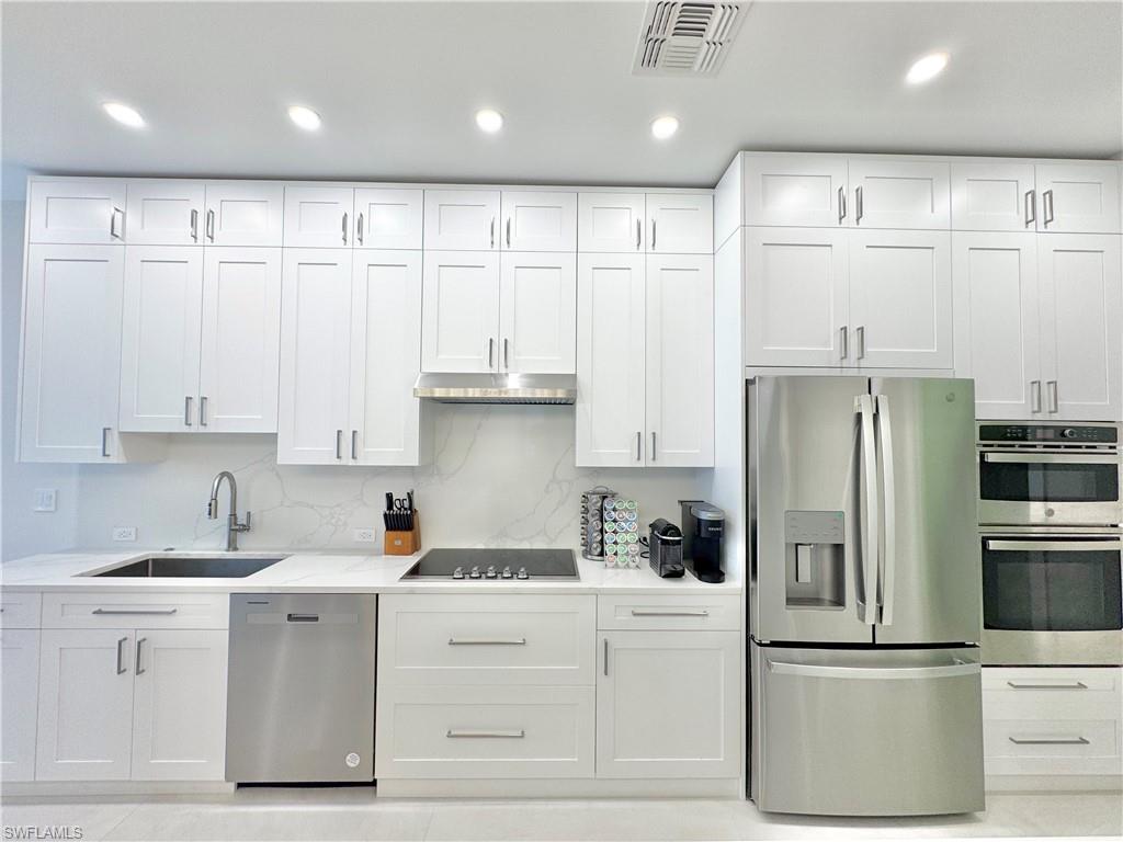 12667 Biscayne Court Naples, FL 34105 - Photo 22 of 39 a kitchen with stainless steel appliances white cabinets and a refrigerator